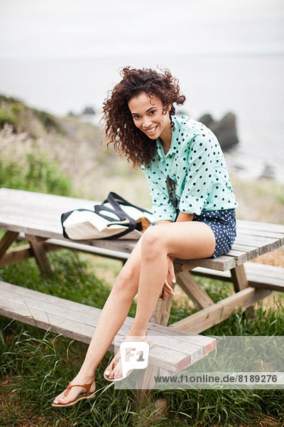 Junge Frau auf Picknicktisch sitzend lächelnd  Portrait