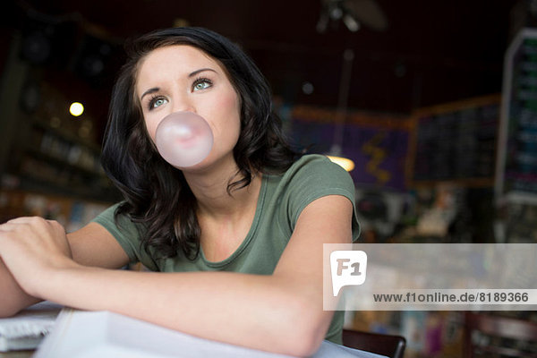 Porträt eines jungen Mädchens  das Bubblegum im Kaffeehaus bläst.