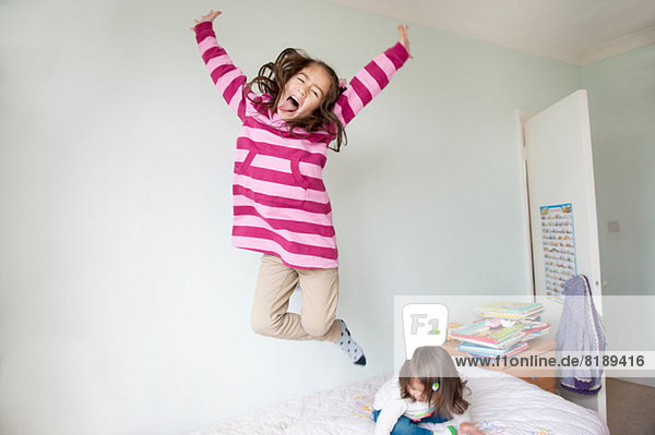 Girl jumping on bed and pulling face