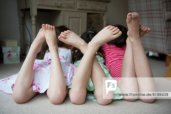 Mädchen auf dem Boden liegend mit erhobenen Füßen