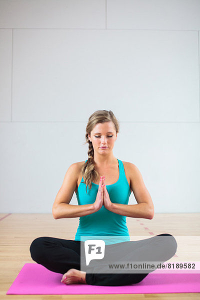 Junge Frau auf Yogamatte in Lotusstellung