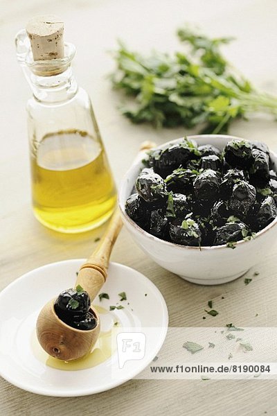 Black olives in a bowl  with parsley and olive oil