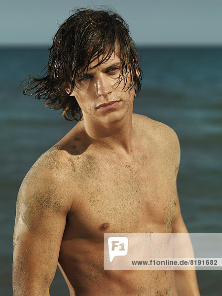 Mann mit nackter Brust und nassen Haaren am Meer