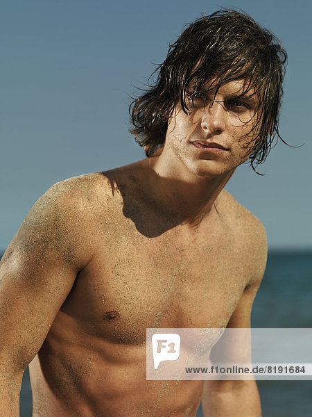 Mann mit nackter Brust und nassen Haaren am Meer