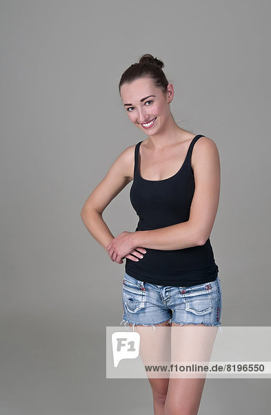 Portrait of young woman posing against grey background  smiling