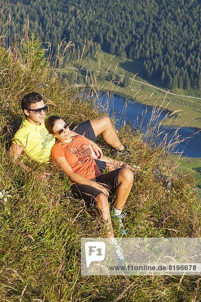 Junges Paar liegt auf einer Bergwiese in der Osterhorngruppe Salzburger Land Österreich