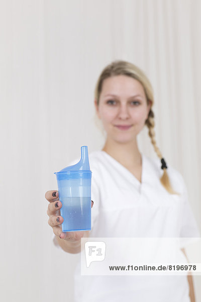 Deutschland  Porträt einer jungen Frau mit blauem Fressnapf und Getränk