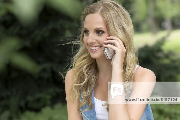 Junge Frau spricht auf dem Handy  lächelnd