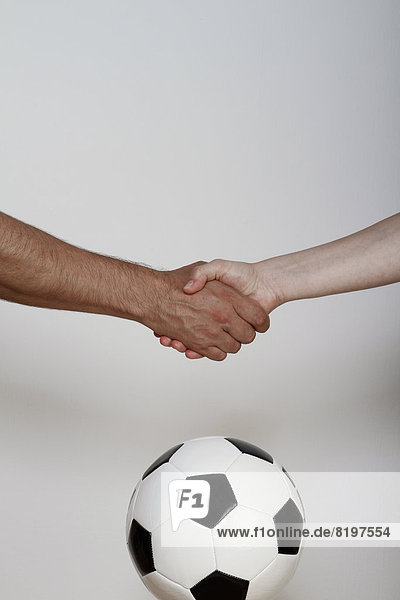Mann und Frau beim Händeschütteln über dem Fußball  Nahaufnahme