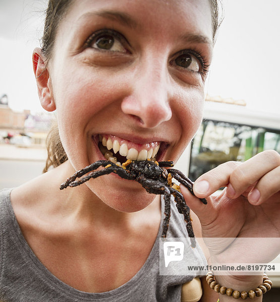 Kambodscha  Junge Frau isst gebratene Vogelspinnen