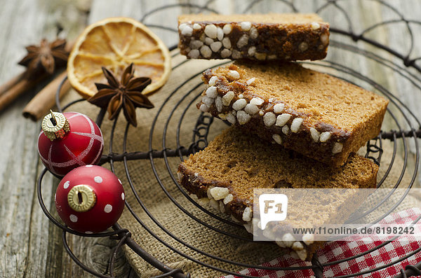 Gingerbread cake with christmas baubles and dried orange  spice on wooden table  close up