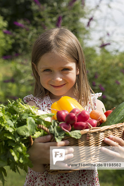 Portrait of girl holding basket full of vegetables  smiling