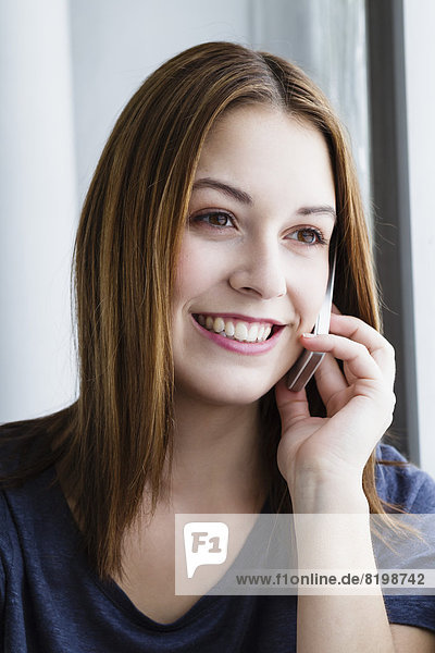 Junge Frau spricht auf dem Handy  lächelnd