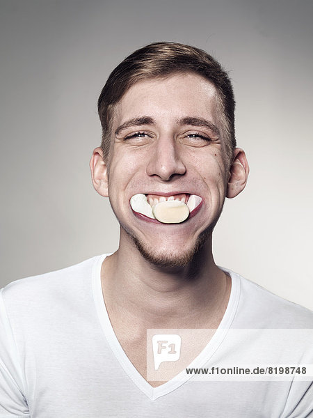 Portrait of Young man mouth suffed with marshmallow and candy