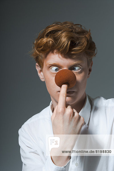 Portrait of young man holding ball on nose  close up