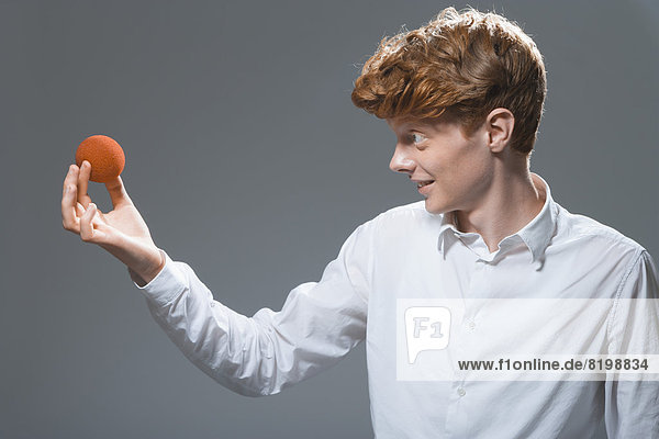 Young man holding and looking at ball  smiling