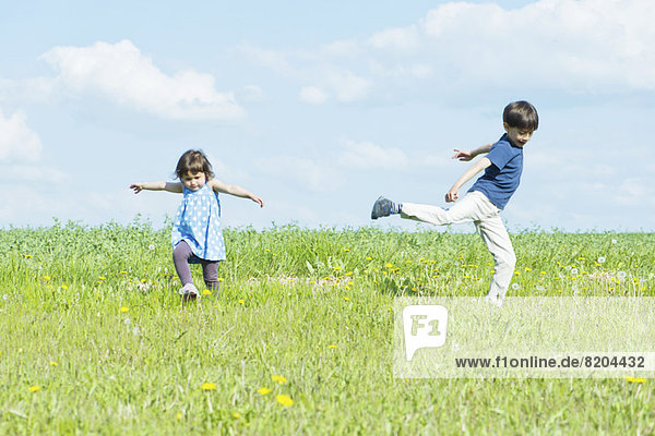 Children running in field with arms out