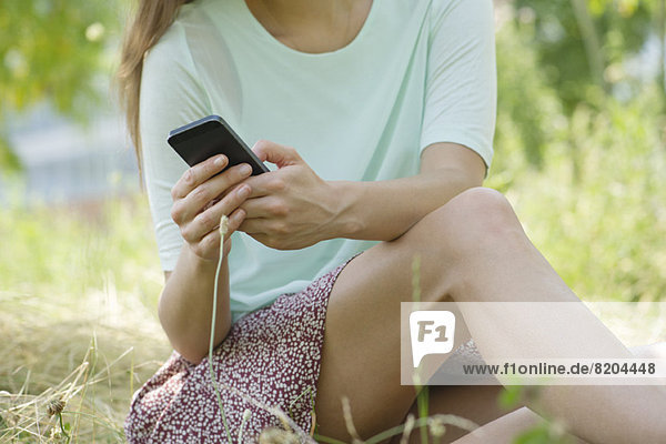 Frau entspannt sich im Freien mit dem Smartphone
