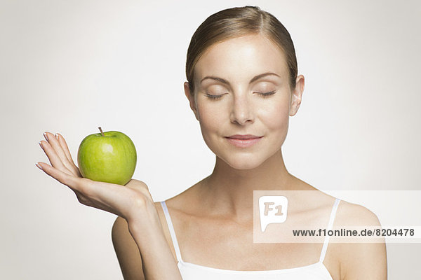 Young woman with eyes closed holding green apple