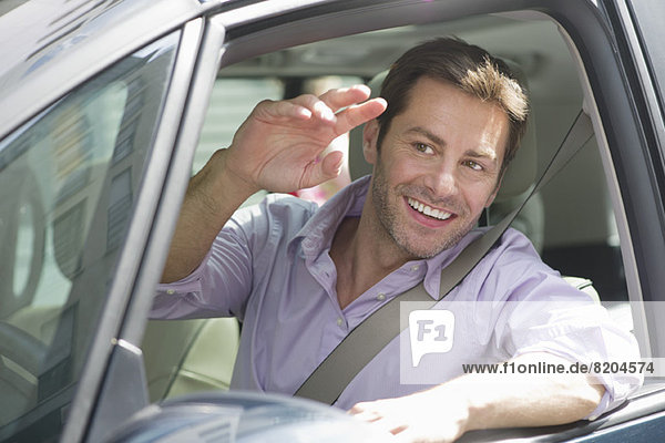 Man driving car  smiling out window and waving