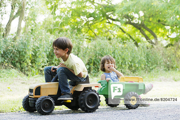 Junge Geschwister fahren auf Spielzeugtraktor