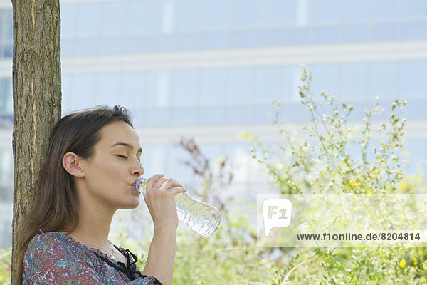 Frau trinkt Flaschenwasser im Freien