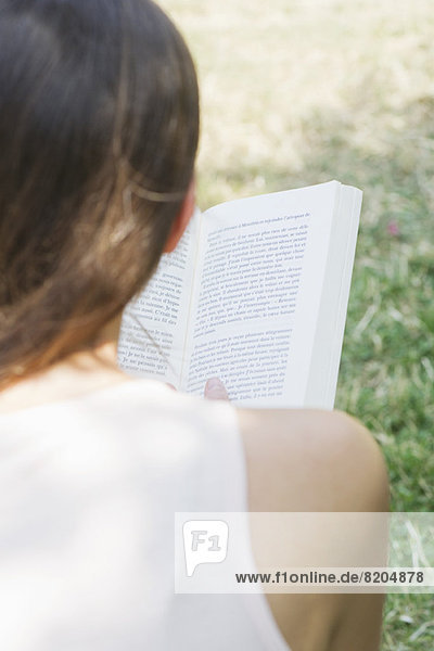 Frau liest Buch im Freien über die Schulter gesehen