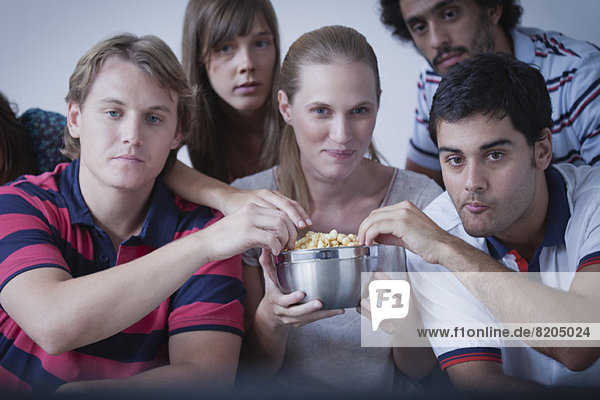 Freunde teilen sich Popcorn und schauen sich gemeinsam einen Film an.