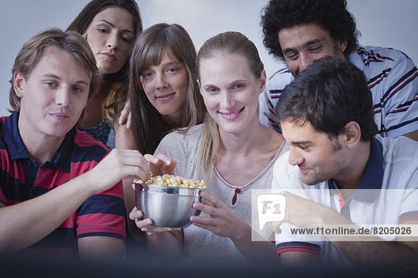 Freunde teilen sich Popcorn und schauen sich gemeinsam einen Film an.