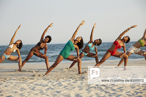 Frauen Übendes Yoga am Strand