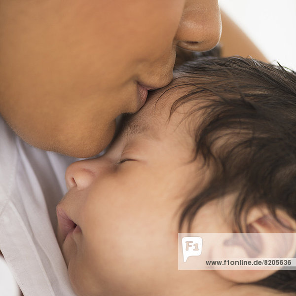 Hispanic mother kissing infant son