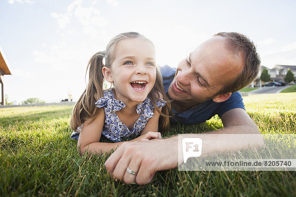 Caucasian father and daughter laying in grass