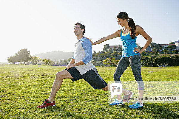 Couple stretching in park