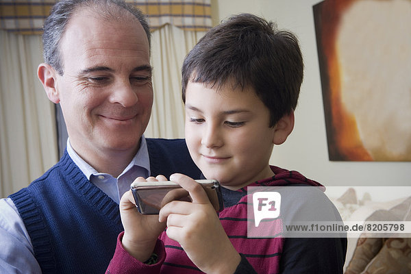 Hispanic father and son using cell phone