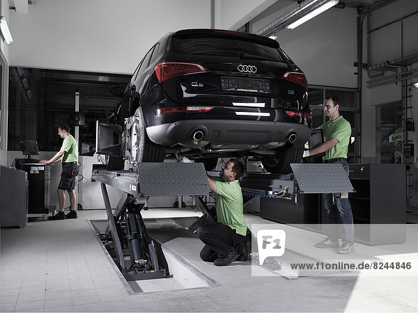 Arbeiter montieren Messscheiben für die Spur-Einstellung  Autowerkstatt VW Strasser