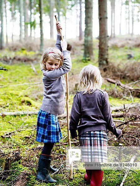 Two girls walking with sticks in forest