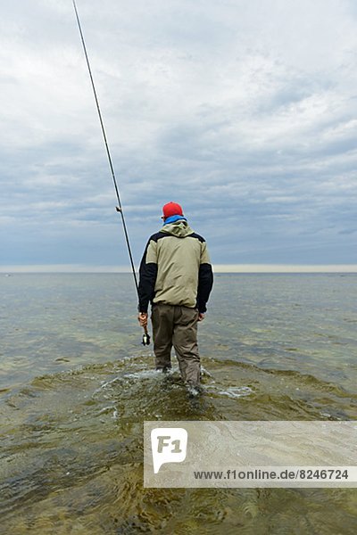 Rear view of man fly fishing in Baltic Sea