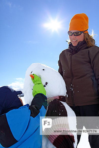 Mother and son building snowman