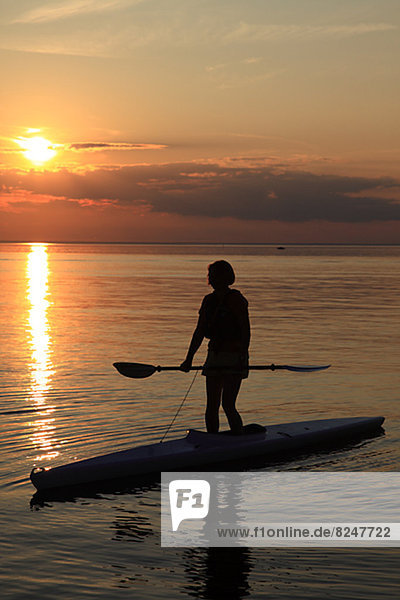 Silhouette of person standing on canoe