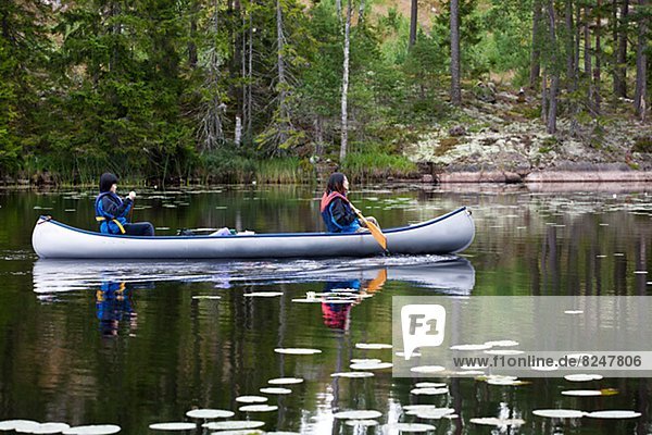 Two women rowing at lake