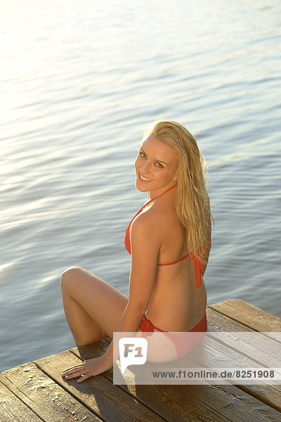 Young blond woman in bikini on a jetty at a lake  Styria  Austria