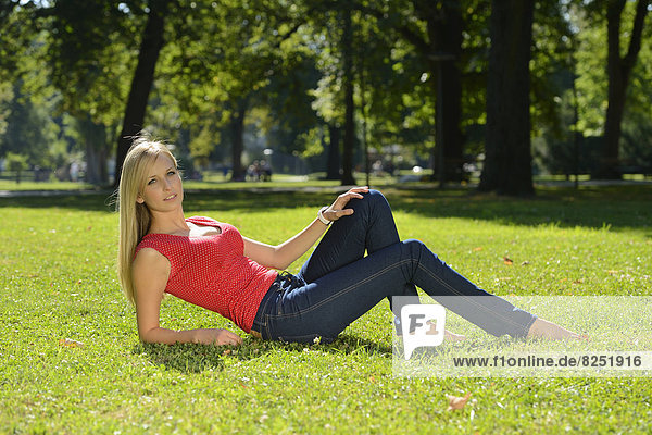 Junge blonde Frau liegt in einem Park
