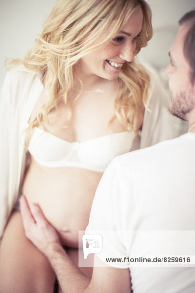 Cropped image of man touching pregnant woman's stomach at home