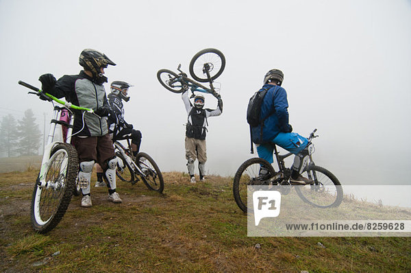 Freunde die sich den Mann ansehen der das Fahrrad auf dem Berg abholt