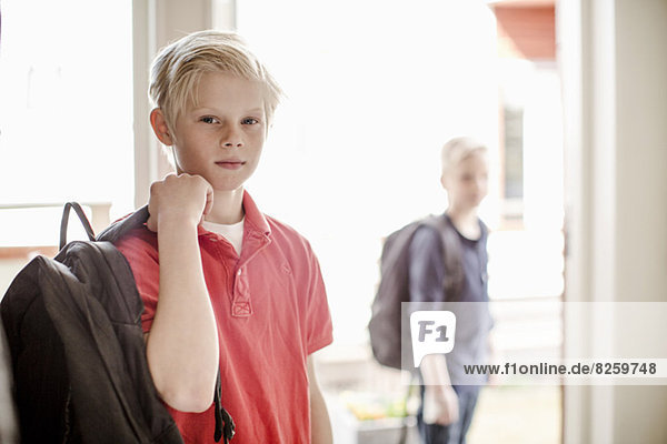 Porträt eines selbstbewussten Jungen mit Rucksack auf dem Weg zur Schule