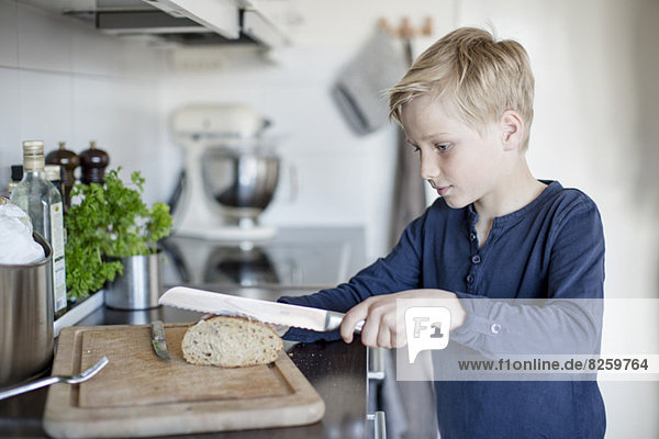 Junge schneidet Brot an der Küchentheke