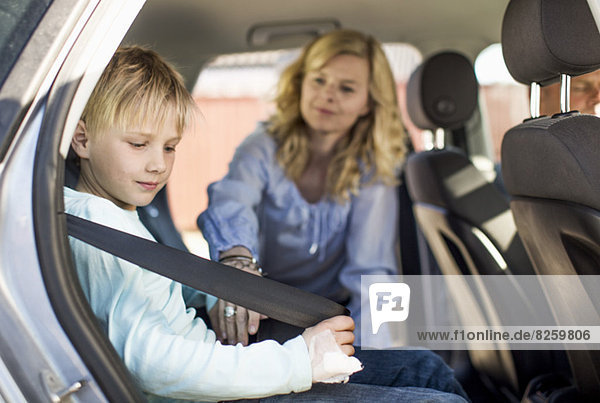Little boy fastening car seatbelt