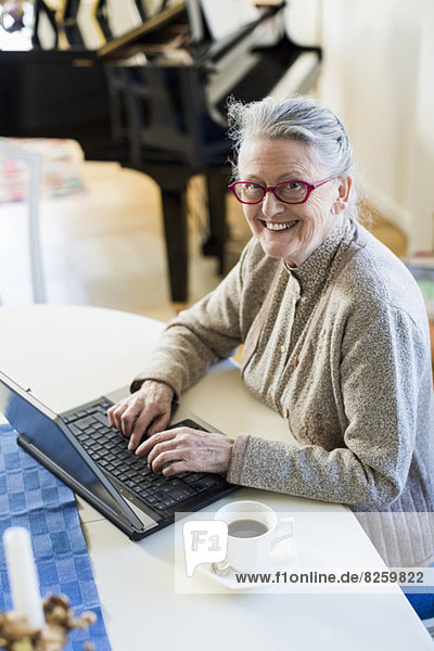 High angle portrait of happy senior woman using laptop at table