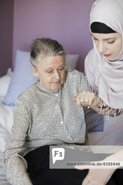 Seniorenfrau mit Betreuerin im Bett
