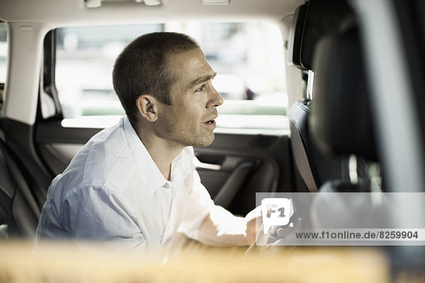Seitenansicht eines Geschäftsmannes mit Mobiltelefon im Taxi
